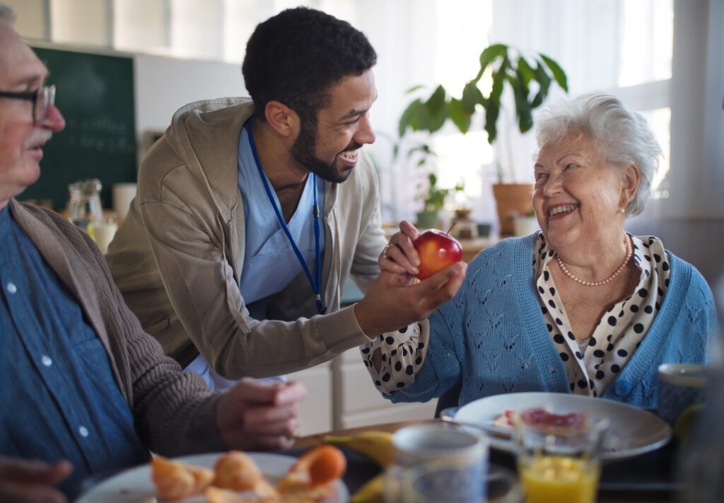 Smiling elderly woman and man enjoying breakfast in nursing home care center.